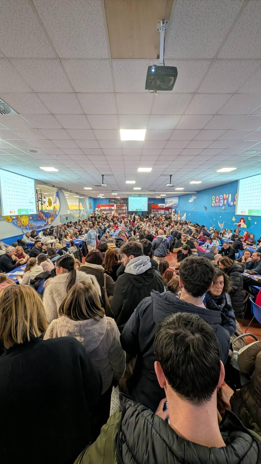 La sala di gioco affollata con i tabelloni